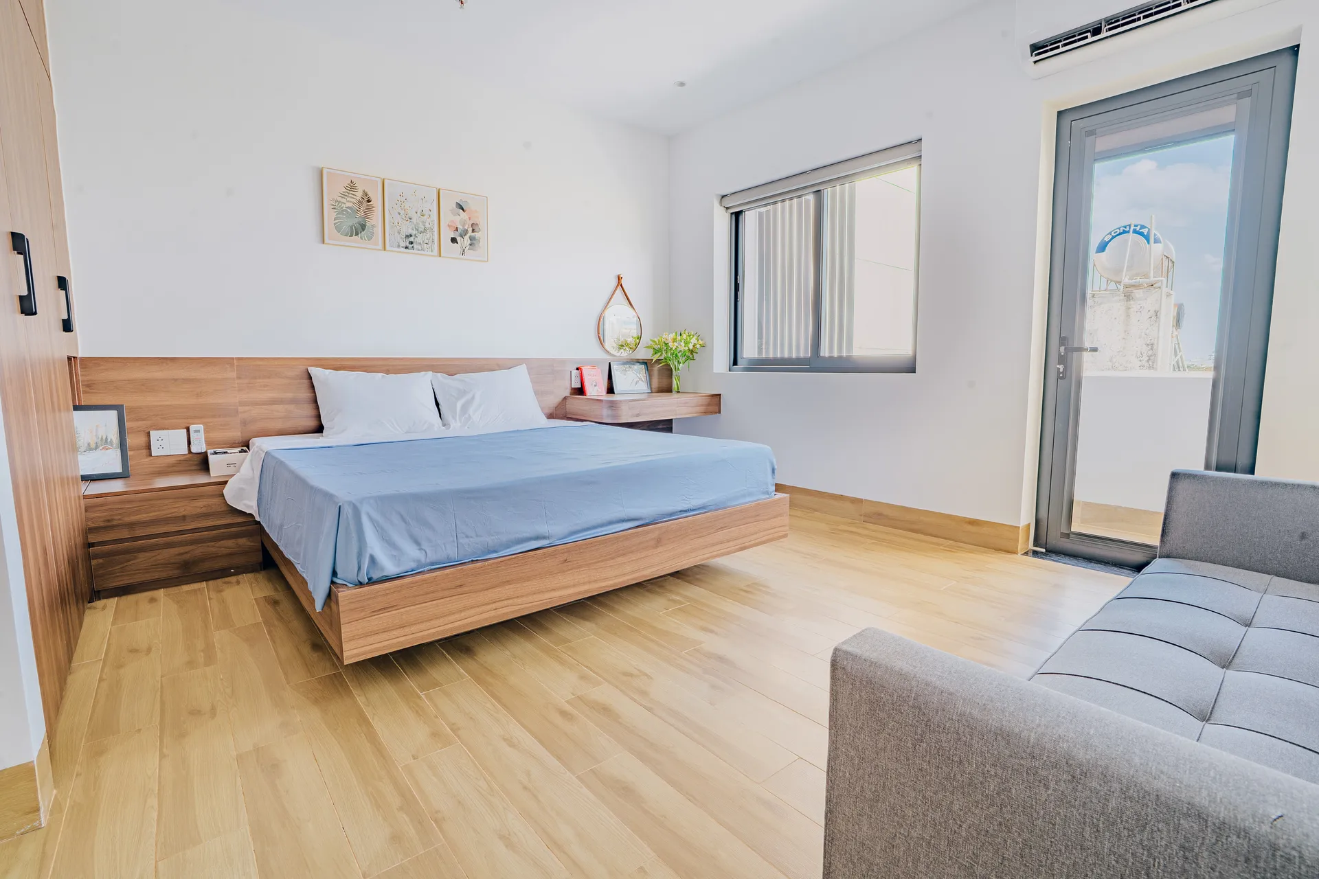 A bright bedroom with a balcony door and a sofa along the wall.